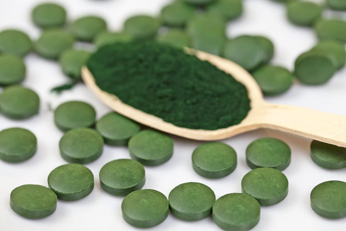 A spoonful of spirulina, on top of spirulina tablets.