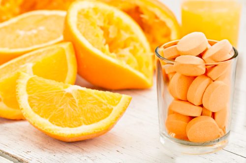 Close-up shot of sliced ​​and diced oranges A glass of orange juice and a glass filled with orange-flavored vitamin C pills.  Eat oranges, drink juice or take pills.